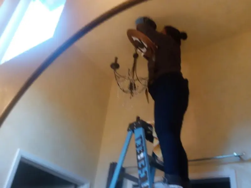 Electrician installing a chandelier in a Preston residence